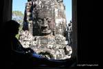 Lecture à l'ombre devant le visage de pierre, Bayon, Angkor Thom, Cambodge.