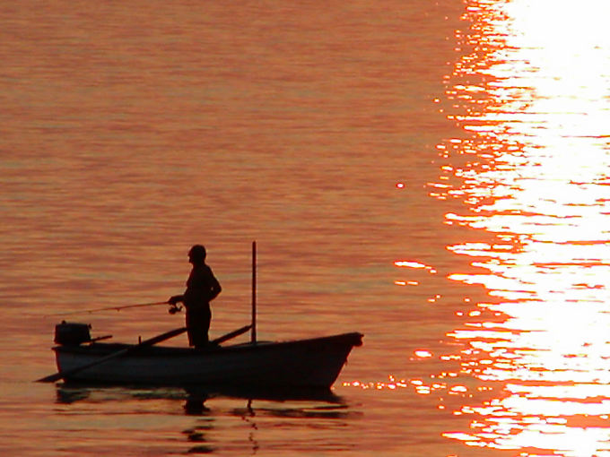Pêcheur à la ligne sur sa barque sur la mer rougie par le soleil, Starigrad - Croatie