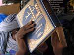 Homme bleu lisant un livre en arabe sur le bateau, Mali.
