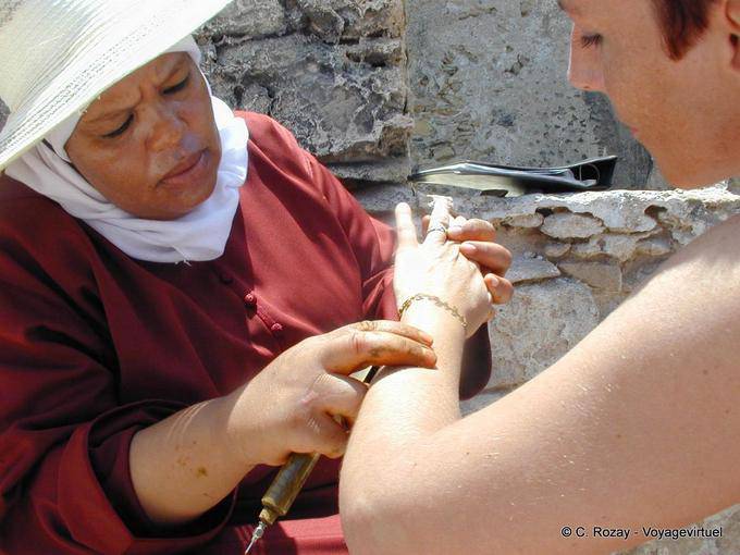 Une tatoueuse au henné officiant près des remparts, Essaouira - Maroc