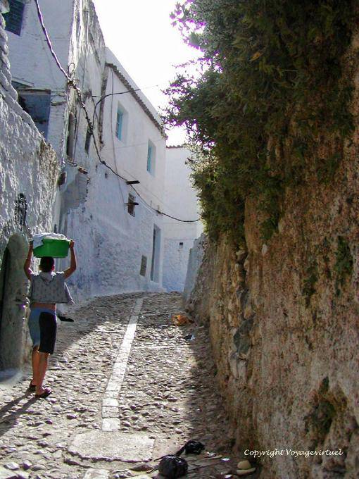 Ruelle pavée de galets et enfant portant le linge sur sa tête, Chefchaouen - Maroc