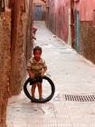 Un enfant jouant avec un pneu, ruelle de la médina, Marrakech, Maroc.
