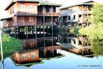 Reflets des habitations à étages sur pilotis, lac Inlé, Birmanie.