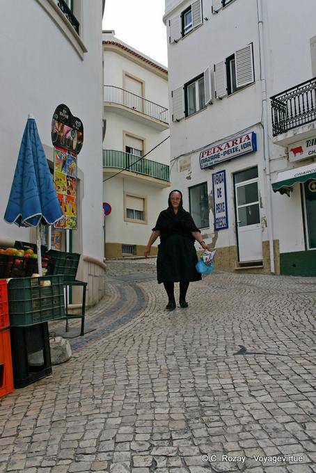 La femme en noir dans la rue pavée, Nazaré - Portugal
