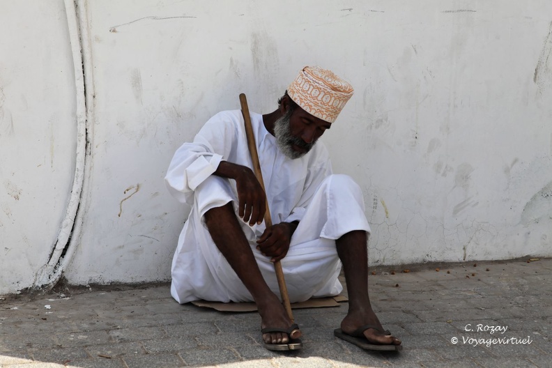 Homme en costume traditionnel omanais, assis par terre, Mutrah Oman مسقط