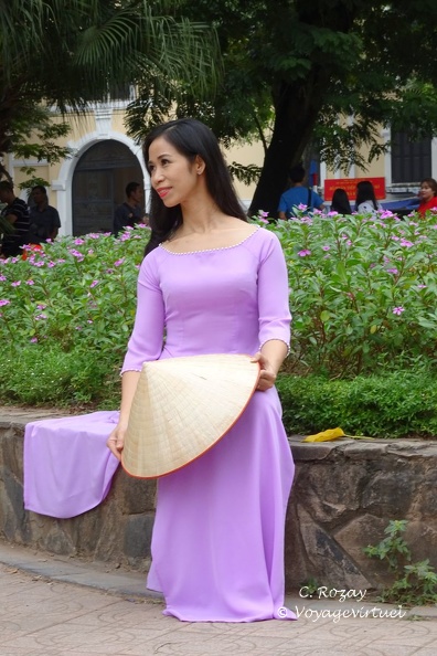 En harmonie avec les fleurs, une jeune femme en robe traditionnelle Ao Dai de couleur parme, avec le chapeau pointu Nón lá, Hanoï. Hanoi Vietnam