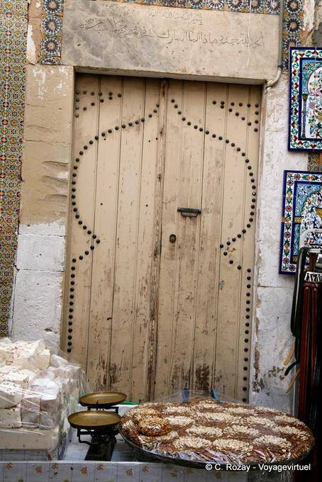 Porte ancienne en bois derrière un étal de gourmandises, médina de Sousse - Tunisie